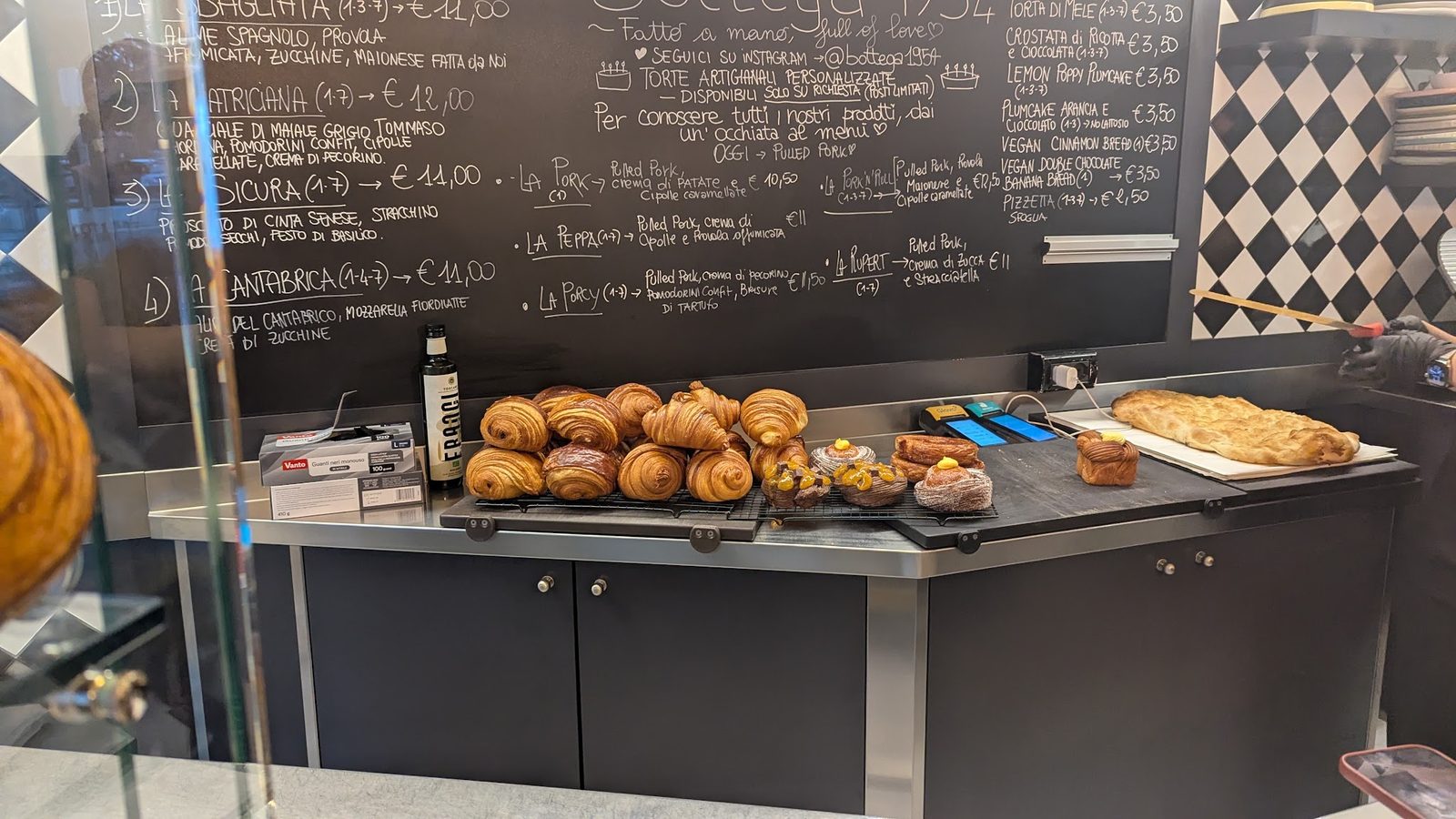 Il banco di Bottega 1954: cornetti e lievitati appena sfornati sotto la lavagna con il menù scritto a mano